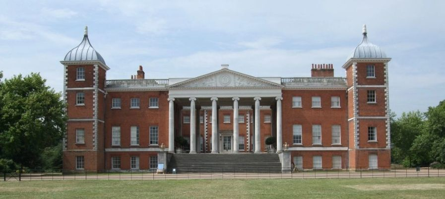 Large red-brick Georgian mansion with two domed corner towers and a grand portico supported by white columns.